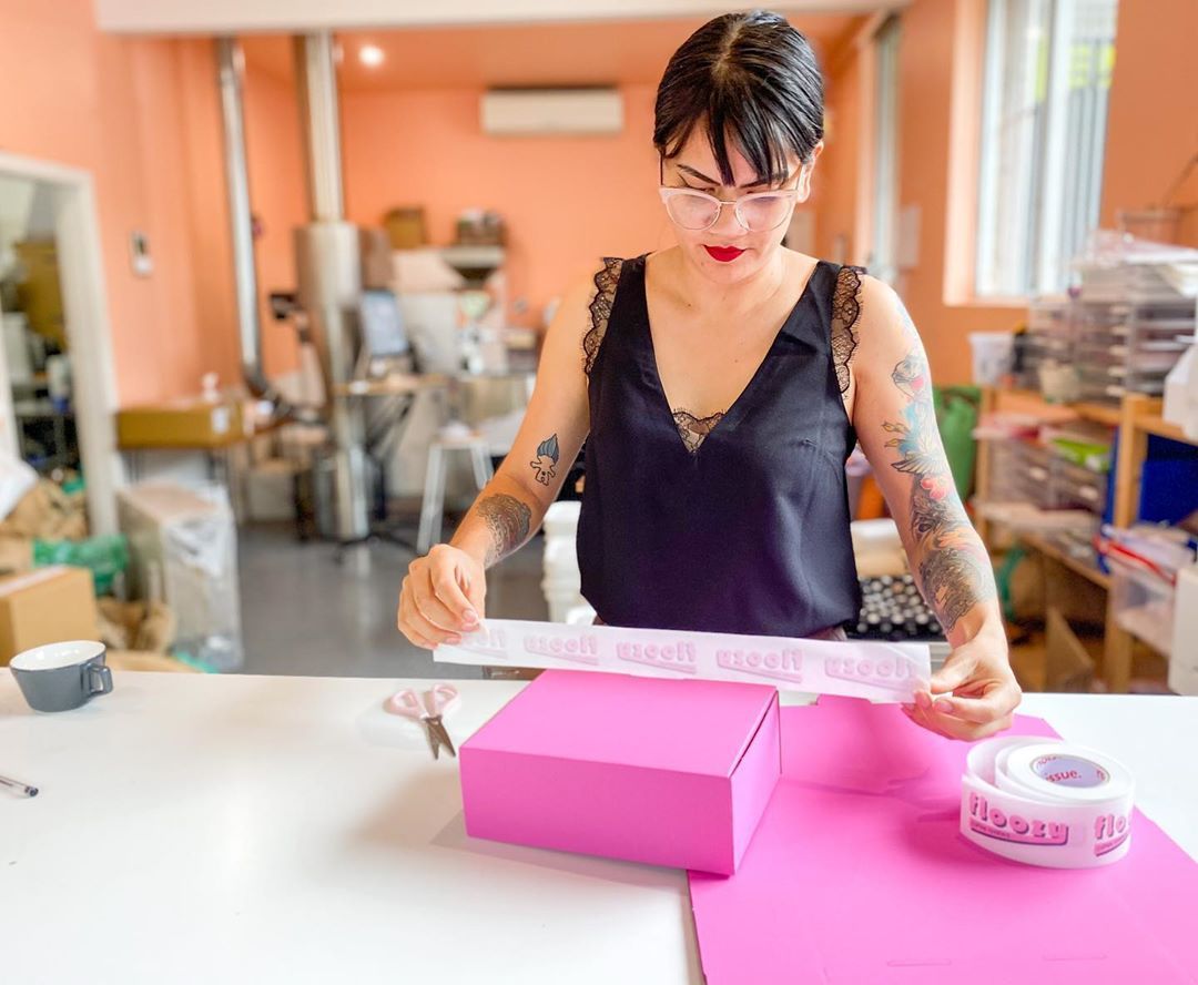 Woman adding custom tape to a shipping box